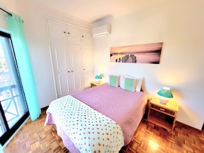 Ein Schlafzimmer mit Bett, Nachttisch, Lampe, einem Gemälde und einem Kleiderschrank.