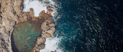 A coastal landscape with rocky formations and clear blue waters.