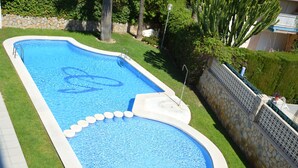 A swimming pool with a stone wall and a grassy area. -  PENTHOUSE WITH LARGE TERRACE, SEA VIEWS, ONE STEP FROM THE BEACH AND WIFI (Campello)