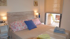 A neatly made bed with patterned bedding, a bedside lamp, and a small table with a chair. -  PENTHOUSE WITH LARGE TERRACE, SEA VIEWS, ONE STEP FROM THE BEACH AND WIFI (Campello)