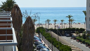 A beachside view with parked cars, palm trees, and a clear blue sky. -  PENTHOUSE WITH LARGE TERRACE, SEA VIEWS, ONE STEP FROM THE BEACH AND WIFI (Campello)