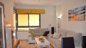 A modern living room with a sofa, a coffee table, and a painting on the wall. -  PENTHOUSE WITH LARGE TERRACE, SEA VIEWS, ONE STEP FROM THE BEACH AND WIFI (Campello)
