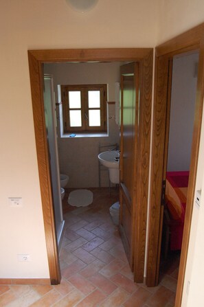 A narrow hallway leading to a bathroom with a window, a sink, and a toilet. - 2 Bed Modernised Barn with Pool, within easy walking distance to Town. (Bagni di Lucca)
