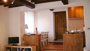 Un espace de vie compact comprenant un escalier en bois, un coin repas avec des chaises, un téléviseur et une bibliothèque.
