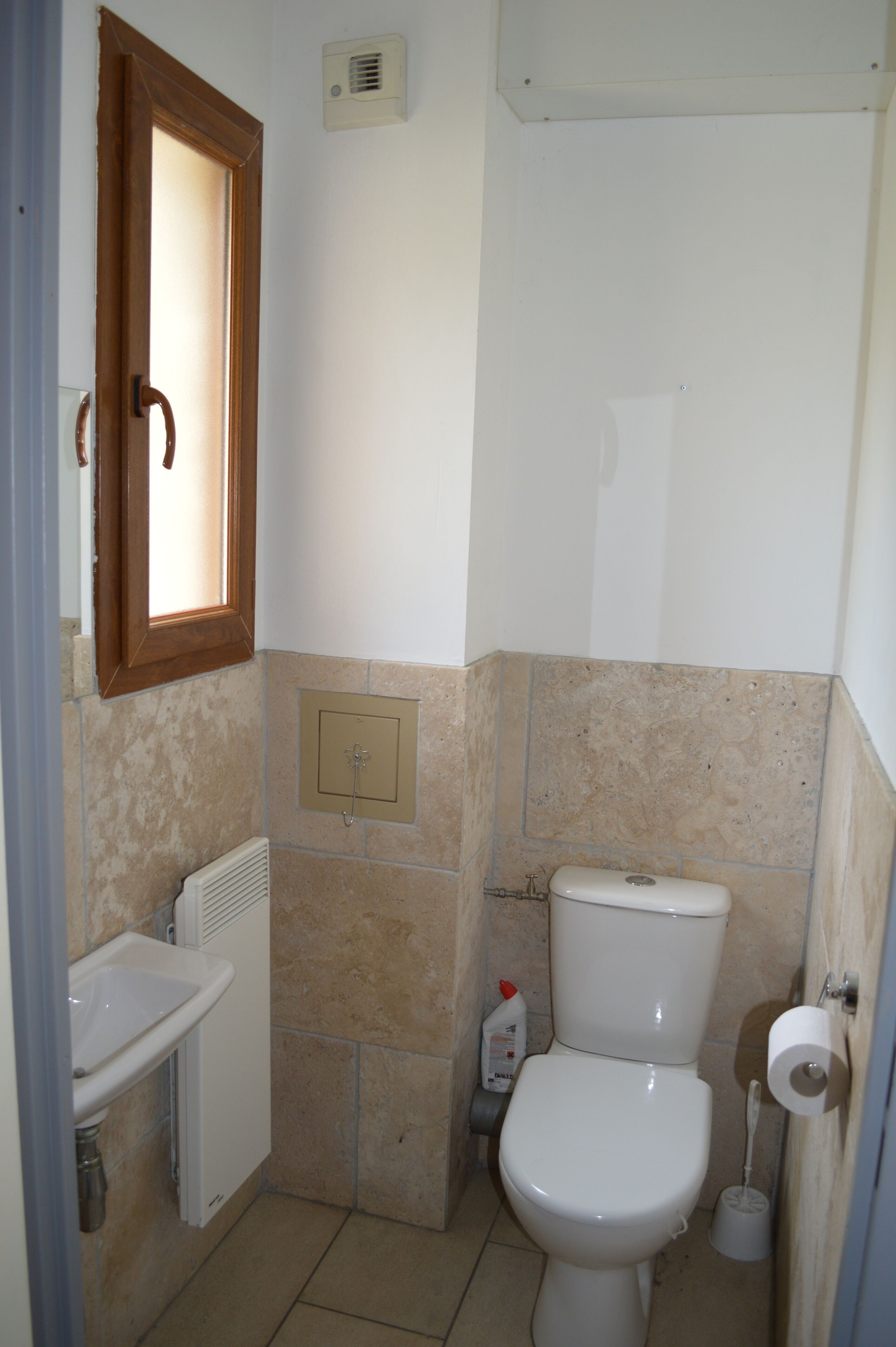 A small bathroom with a white sink, a toilet, and a window above the sink.