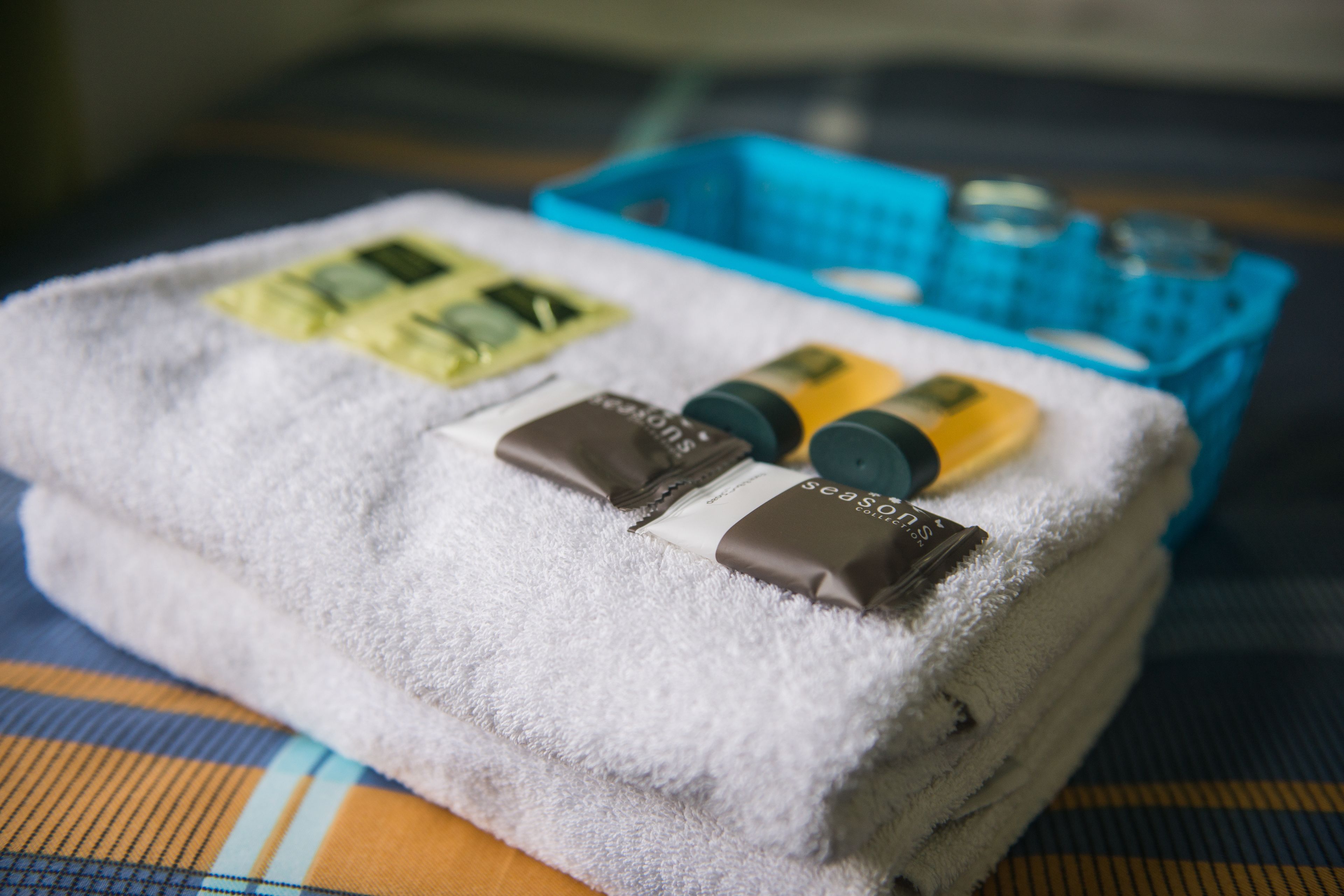 A neatly folded white towel with toiletries on a checkered tablecloth.
