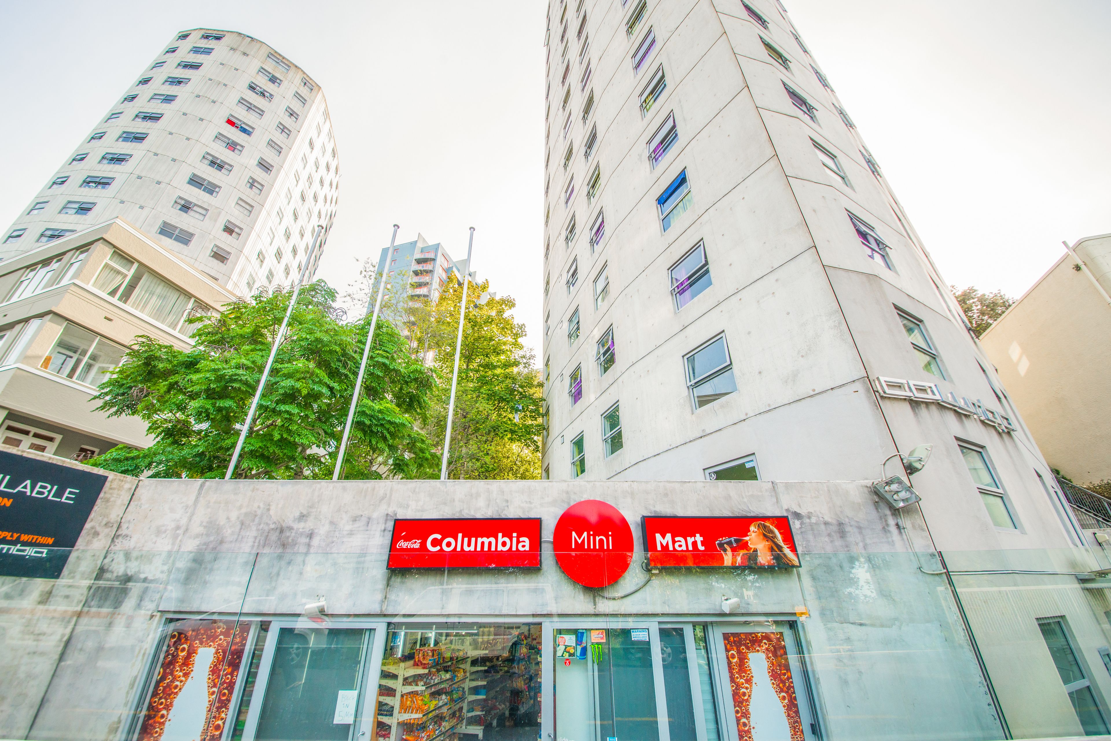 Un edificio a più piani con vetrina che mostra un cartello Coca-Cola, un Mini Mart e un grande logo circolare rosso.