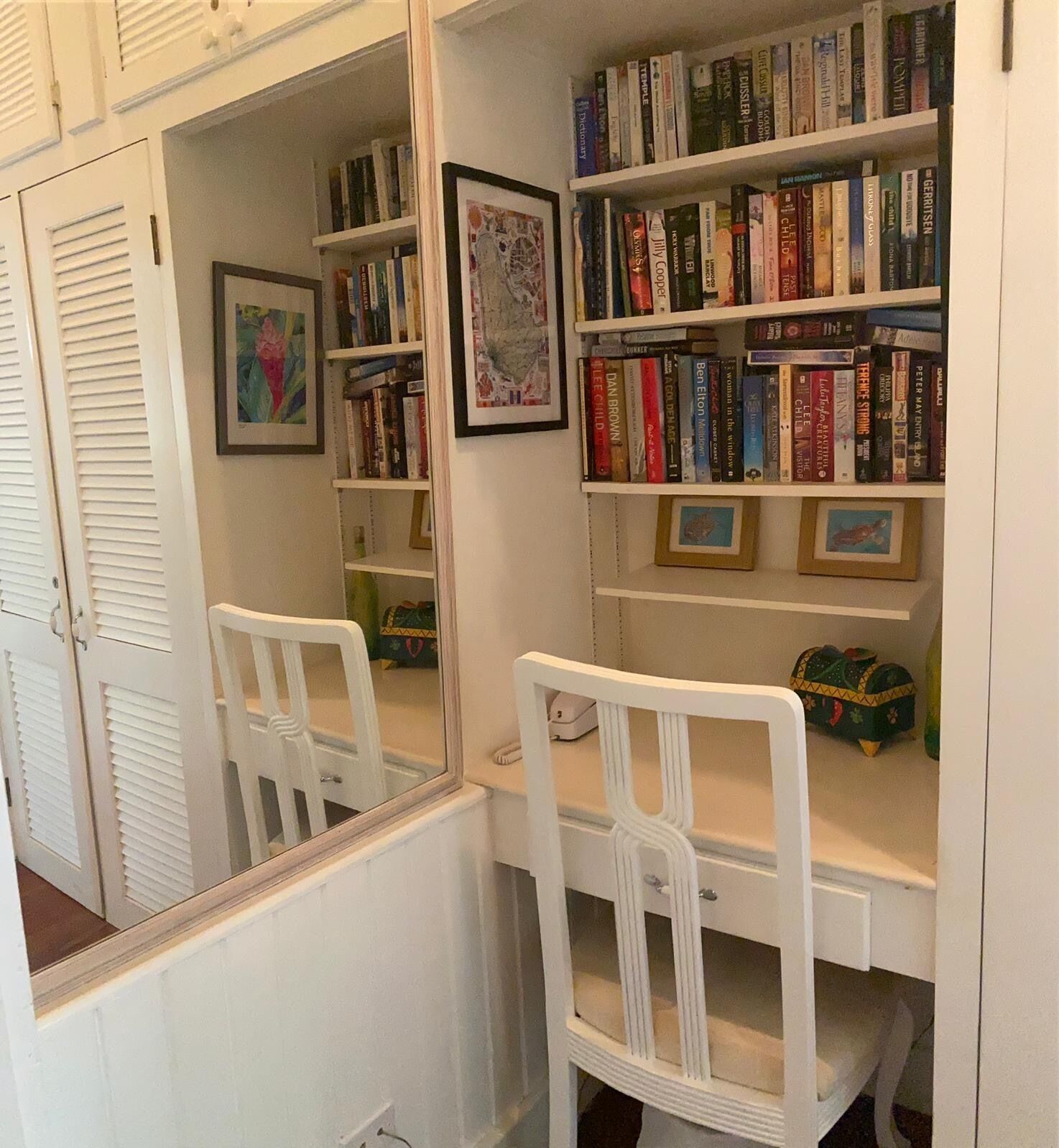 Une pièce avec une armoire blanche, un miroir et une bibliothèque remplie de livres.