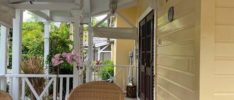A covered patio with wicker furniture, a ceiling fan, and a potted plant.