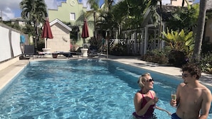 Ein Schwimmbecken mit klarem Wasser, umgeben von Palmen und einem überdachten Sitzbereich.