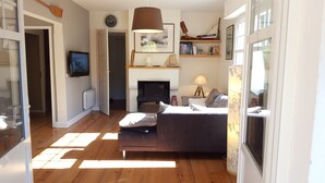 A living room with a fireplace, a sofa, a television, and a bookshelf.