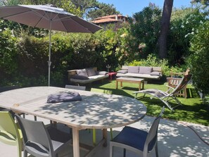 Um pátio com mesa redonda, cadeiras, um sofá e um guarda-sol.