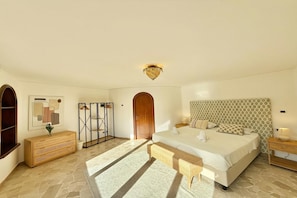 A bedroom with a large bed, a wooden wardrobe, a mirror, and a patterned headboard. - Villa Isola Verde, Valsolda, Italy (Valsolda)