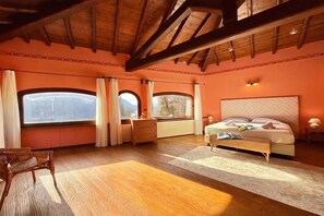 A bedroom with a large bed, two windows, a dresser, and a chair. - Villa Isola Verde, Valsolda, Italy (Valsolda)