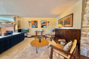 A living room with a sofa, a coffee table, and a TV. There are paintings on the wall and a lamp. - Villa Isola Verde, Valsolda, Italy (Valsolda)
