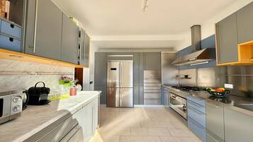 Une cuisine moderne avec des meubles gris, des appareils en acier inoxydable et un plan de travail en marbre.