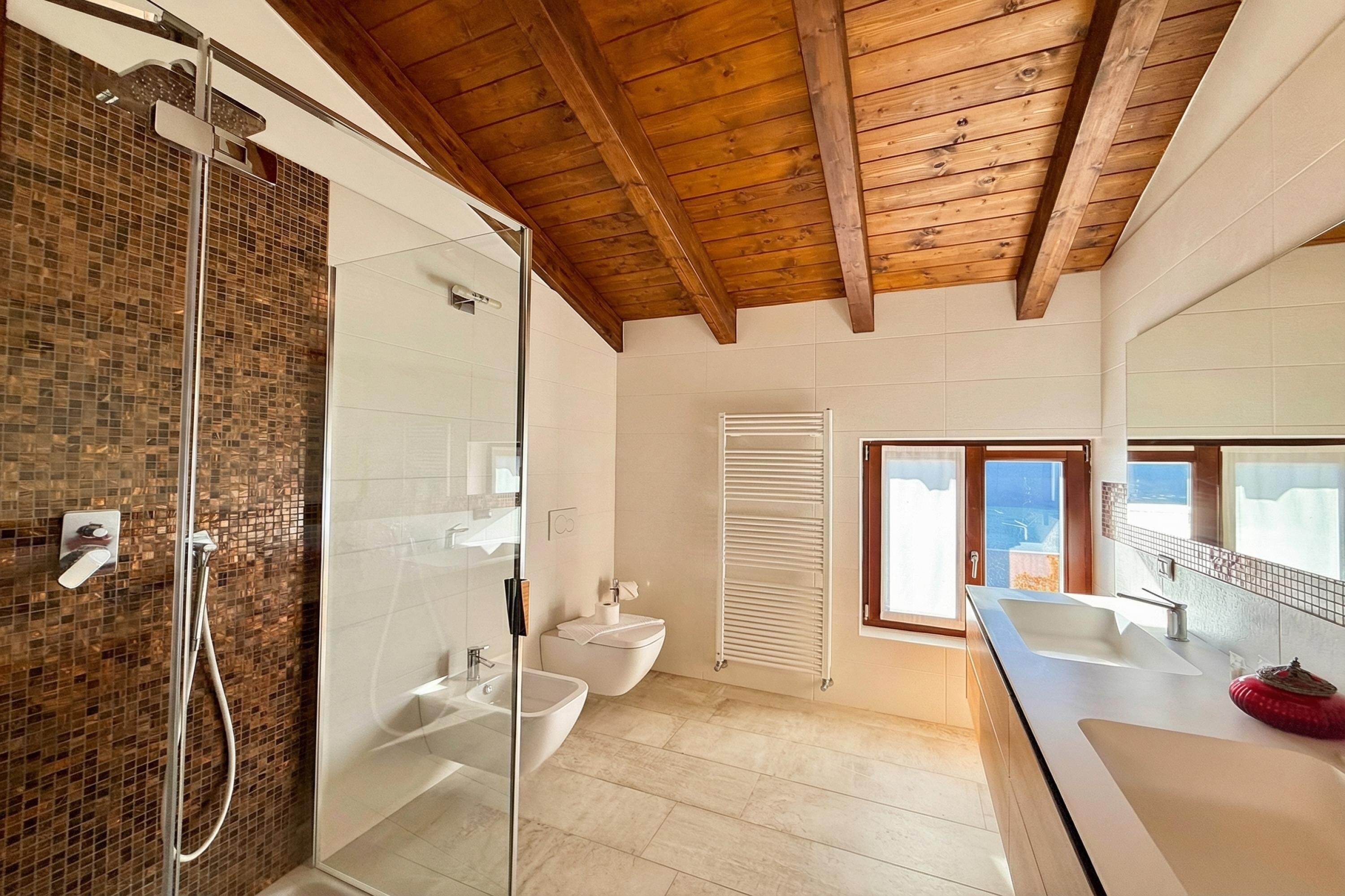 Une salle de bain moderne avec une douche à parois de verre, un lavabo blanc et un grand miroir.