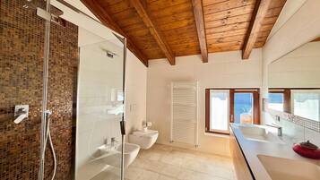 Une salle de bain moderne avec une douche à parois de verre, un lavabo blanc et un grand miroir.