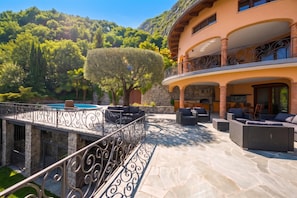 A luxurious outdoor patio with stone flooring, outdoor furniture, and a swimming pool. - Villa Isola Verde, Valsolda, Italy (Valsolda)