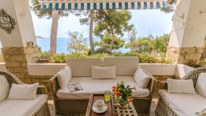 A wicker sofa with white cushions and a tray table with a cup and flowers. - Wonderful Villa, private pool, seafront, garden, excellent views to the bay (Playa Albufereta- Alicante)