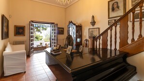 A grand piano in a spacious room with a staircase, framed pictures on the walls, and a chandelier. - Wonderful Villa, private pool, seafront, garden, excellent views to the bay (Playa Albufereta- Alicante)