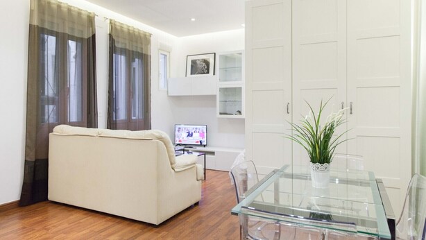 Un salon moderne avec un canapé, une table à manger en verre et un téléviseur.
