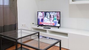 Un salon moderne avec une table basse en verre, un téléviseur à écran plat et des étagères intégrées.