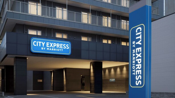 Un edificio de varios pisos con un letrero que dice 'CITY EXPRESS BY MARRIOTT', indicando que es un hotel.