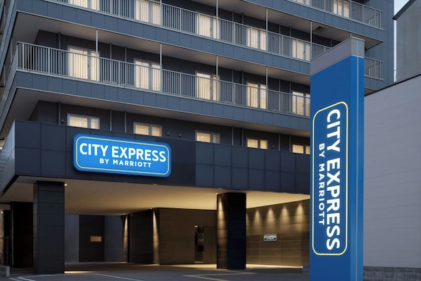 Ein mehrstöckiges Gebäude mit einem Schild für 'CITY EXPRESS BY MARRIOTT', das ein Hotel kennzeichnet.