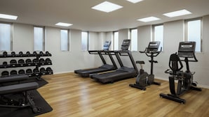 Un gimnasio con cintas de correr, elípticas y una zona de pesas.