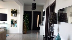 A modern living room with a sofa, a coffee table, a TV, and decorative plants. - LUXURY SEAFRONT APARTMENT WITH POOL (Saint Paul's Bay)