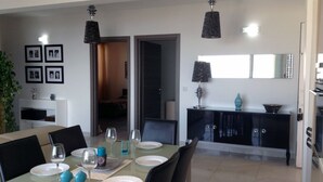 A dining area with a table set for four, chairs, and a kitchen area in the background. - LUXURY SEAFRONT APARTMENT WITH POOL (Saint Paul's Bay)