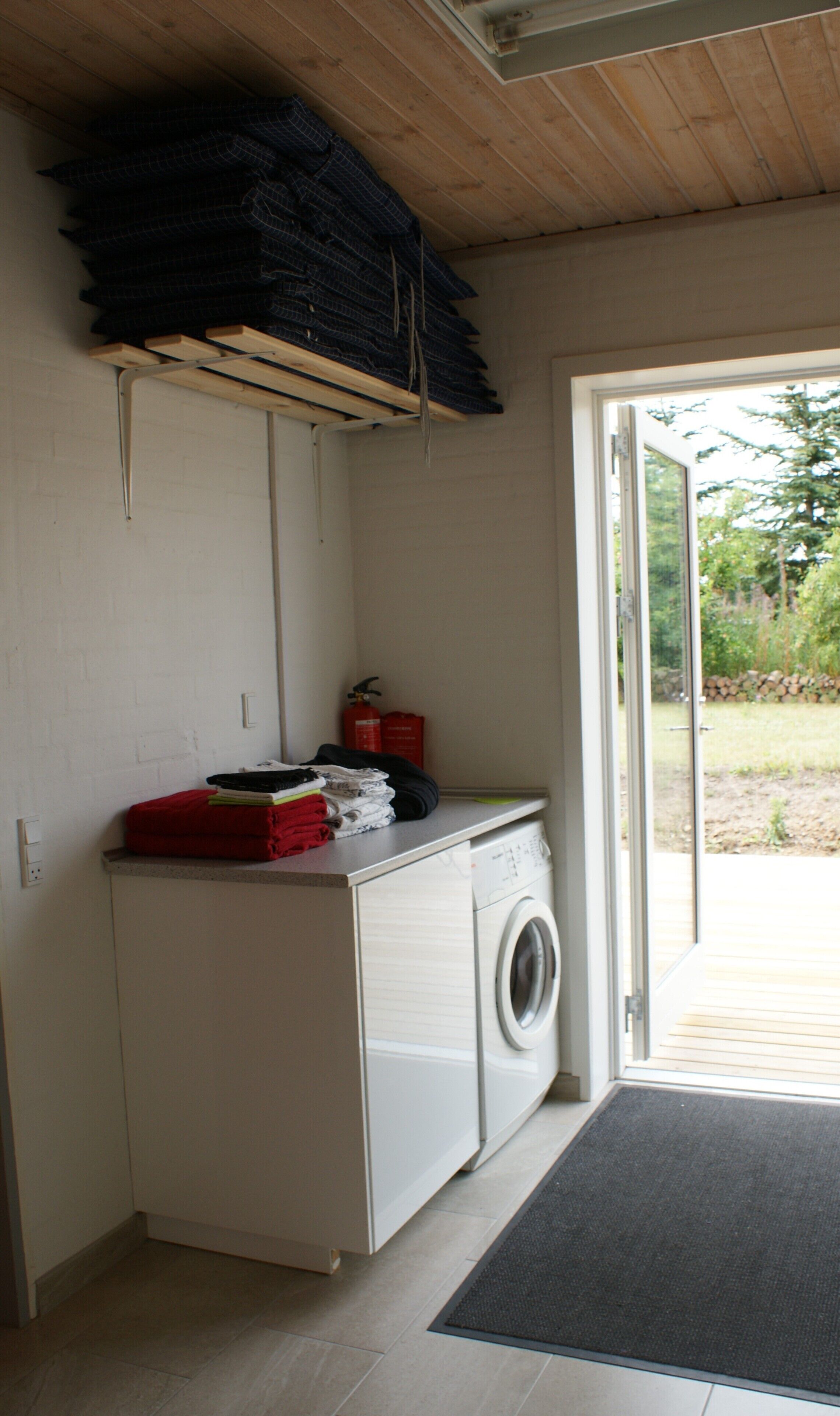 A laundry room with a washing machine, a drying rack, and a fire extinguisher.