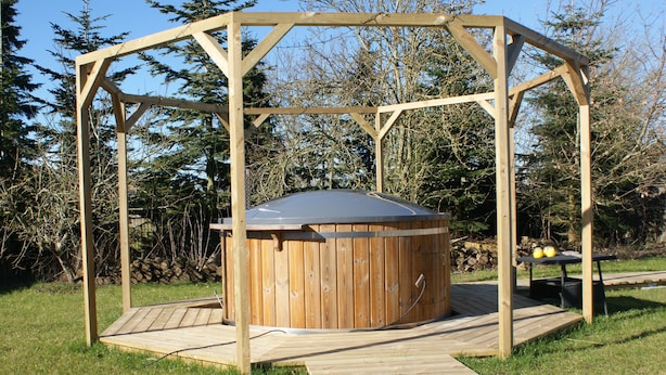 A wooden hot tub with a pergola structure, surrounded by a grassy area and trees. - Wonderfull holiday house                                           (Nykøbing Mors)