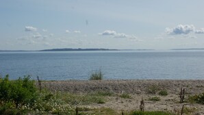 A beach with a view of the sea and a distant landmass. - Wonderfull holiday house                                           (Nykøbing Mors)