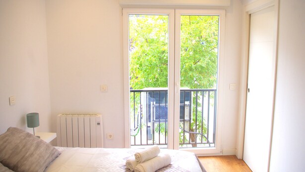 Quarto com cama, radiador, janela e porta.