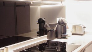 Uma cozinha moderna com um fogão por indução preto, uma cafeteira e uma torradeira.