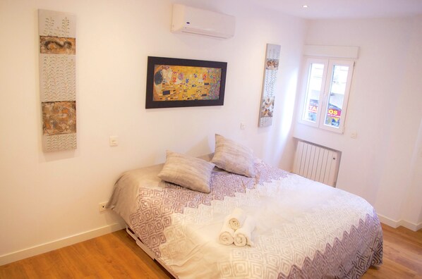 A bedroom with a large bed, patterned bedding, a framed artwork, and a window with a view. - NEW! AMAZING LUXURIOUS APARTMENT IN MADRID CENTER (Madrid)