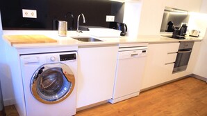 Cozinha compacta equipada com máquina de lavar, lava-louças, micro-ondas e cafeteira.