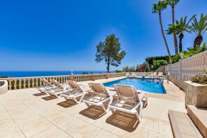 A poolside area with lounge chairs and a view of the sea. - Villa for rent in Benissa, GARROFER (Benissa)