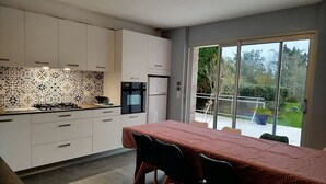 A modern kitchen with white cabinets, a patterned backsplash, and a dining area with a table and chairs. - House with garden  3 stars (Névez)