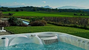 Een hottub met uitzicht op een groen veld en bergen op de achtergrond.