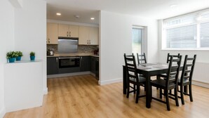 A modern kitchen with dark cabinets, a stainless steel refrigerator, and a wooden dining table with chairs. - Luxury newly renovated 3-bedroom, 2-bathroom mews house in Hampstead London (London)