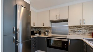 A modern kitchen with stainless steel appliances, dark cabinetry, and a wood floor. - Luxury newly renovated 3-bedroom, 2-bathroom mews house in Hampstead London (London)