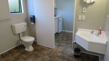 Een badkamer met toilet, wastafel en een kleine koelkast.