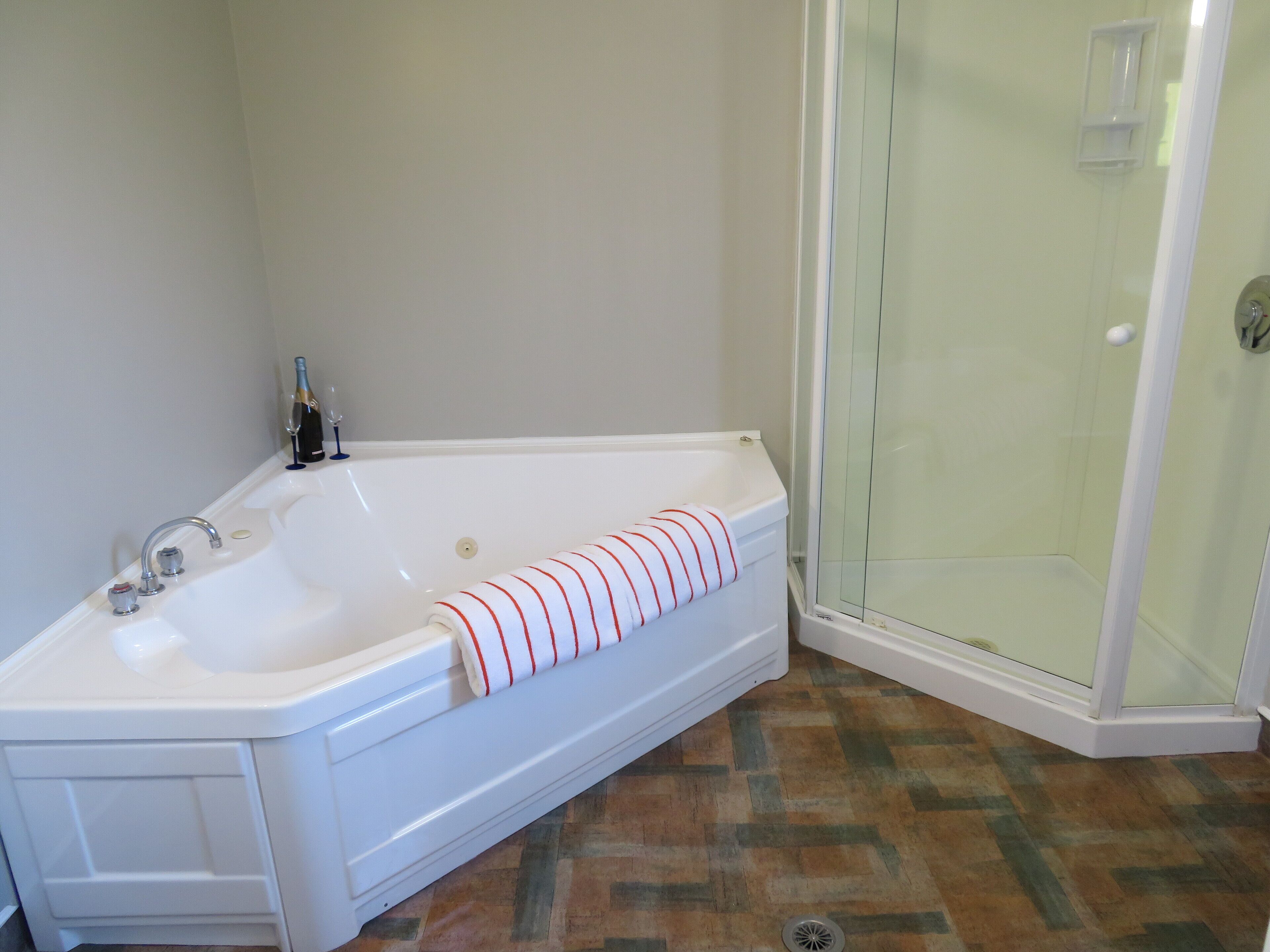 A bathroom with a white bathtub, a glass shower enclosure, and a patterned floor.