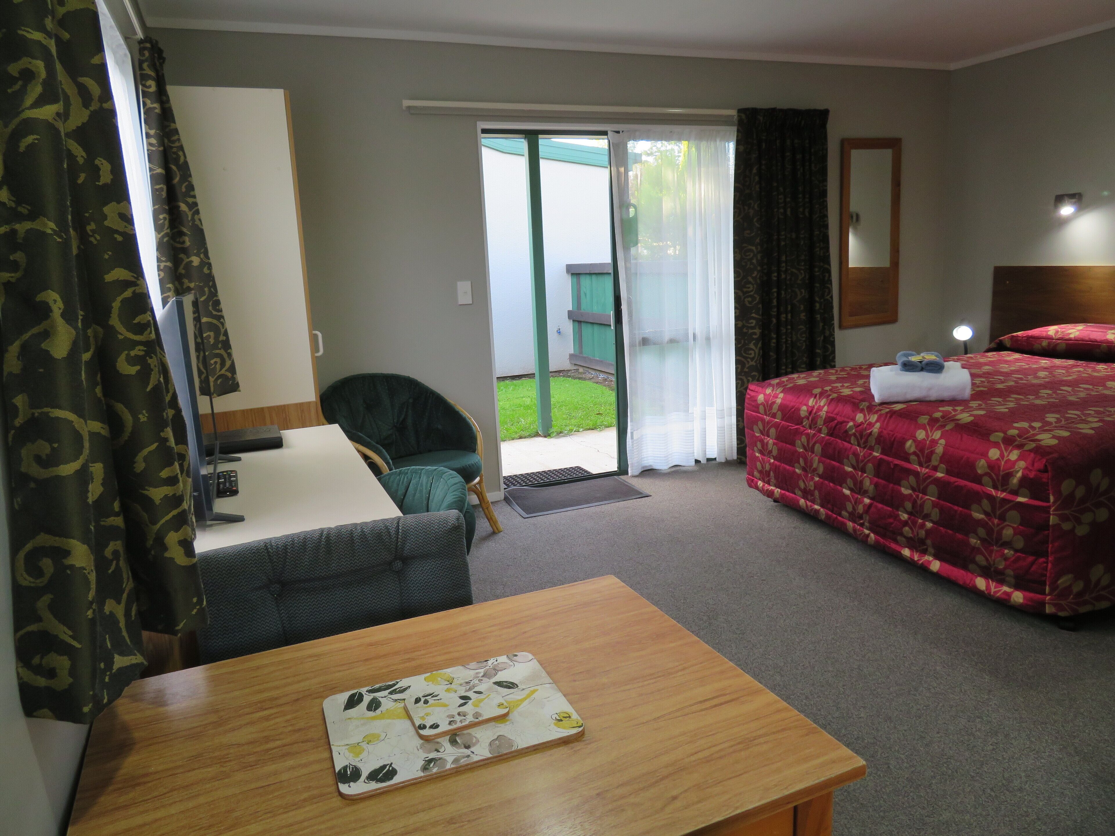 Habitación de hotel con cama, escritorio, silla, mesa y vistas al exterior.