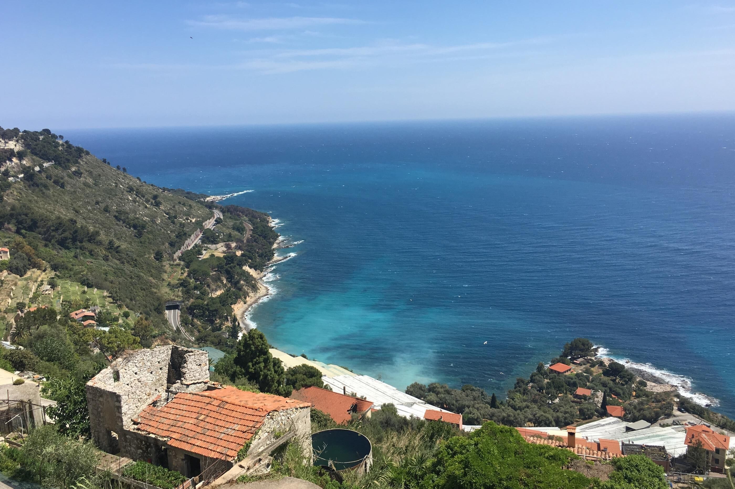 A coastal village with stone buildings, a winding road, and a view of the sea.