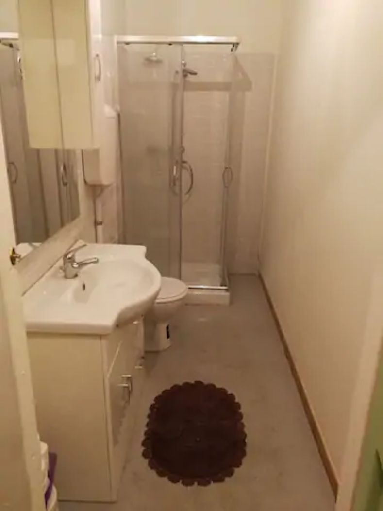 Un baño con lavamanos, inodoro y cabina de ducha de vidrio.