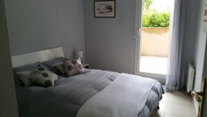 A bedroom with a bed, pillows, a nightstand, a window, and a view of greenery outside. - Very nice spacious and bright apartment T3 any comfort (terrace 25m2) (Hyères)